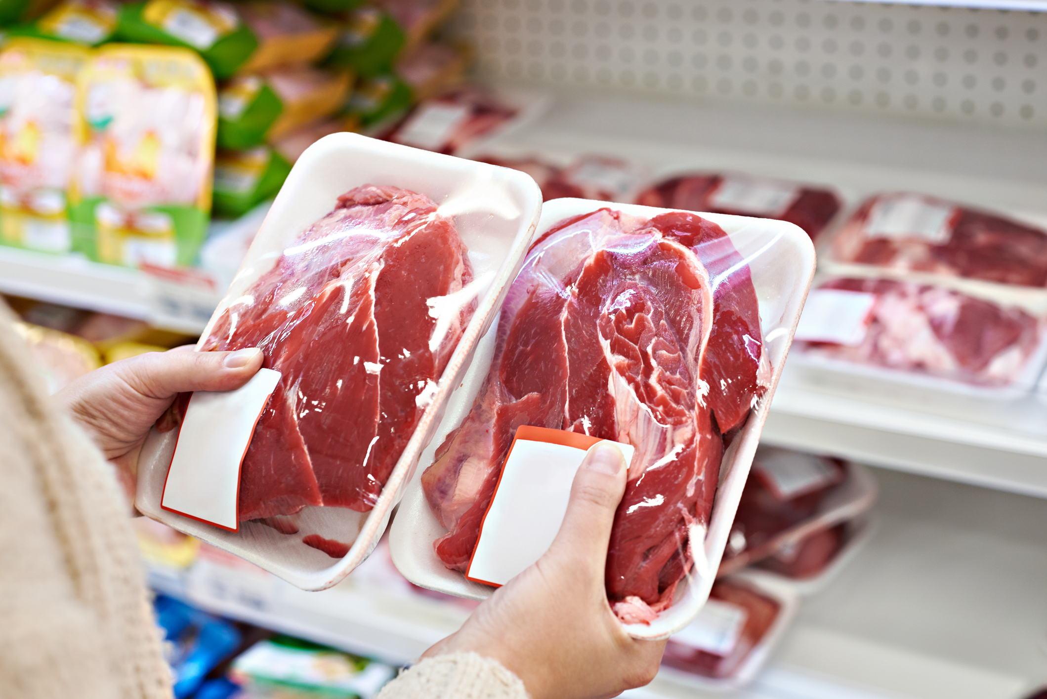Image of buyer hands with beef meat packages at grocery