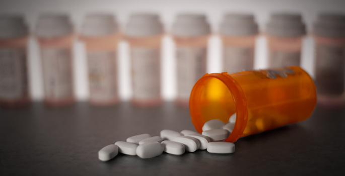 Prescription medication is strewn about, with pill bottles in the deep background. (Getty Images)