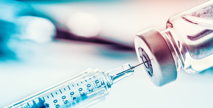 Close-up medical syringe drawing medication from a vial