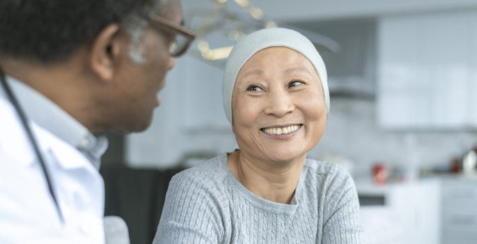 A Korean woman with cancer is meeting with her doctor. Chemotherapy treatment is going well. The patient is smiling at her doctor as he shares with her positive news. (A Korean woman with cancer is meeting with her doctor. Chemotherapy treatment is go