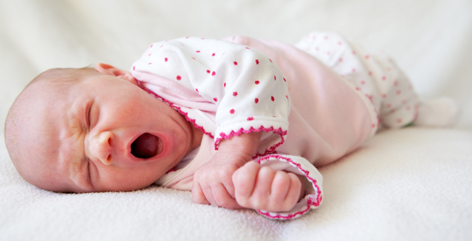 Yawning newborn caucasian baby.