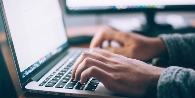 Hands typing on a laptop computer