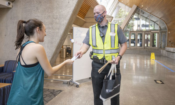 COVID ambassador handing face mask to student