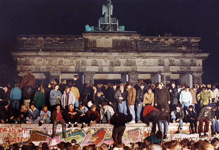 photo of German citizens atop the Berlin Wall in 1989