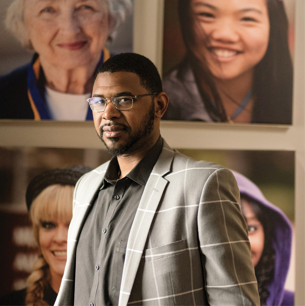 photo of Shan Foster standing before a series of portraits of women