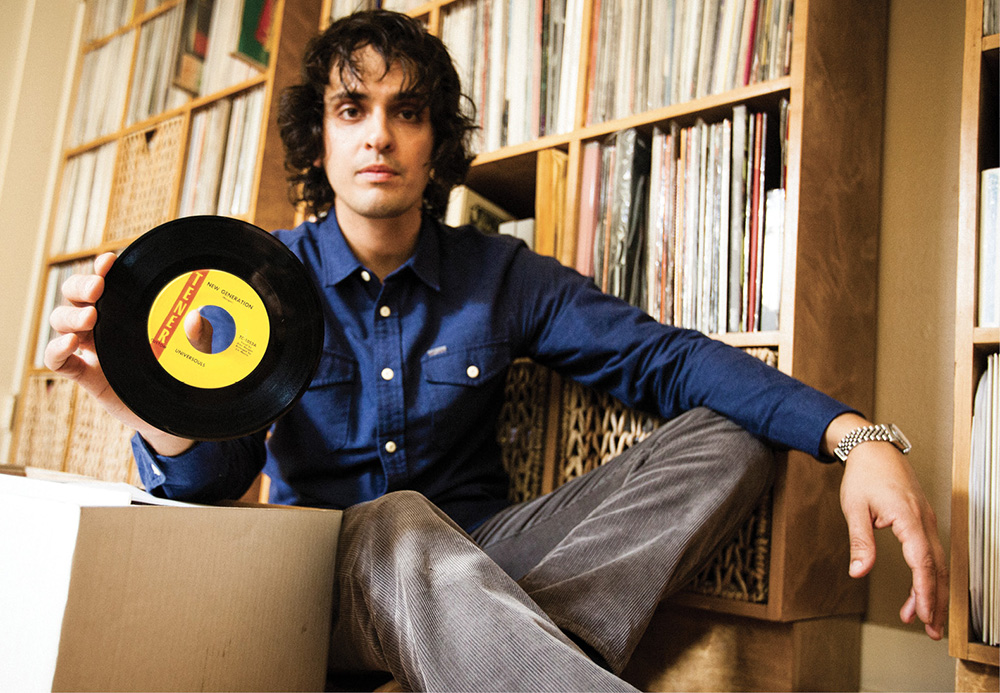 photo of Egon Alapatt sitting in front of his vinyl collection