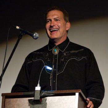 John Bloom, aka Joe Bob Briggs, at podium