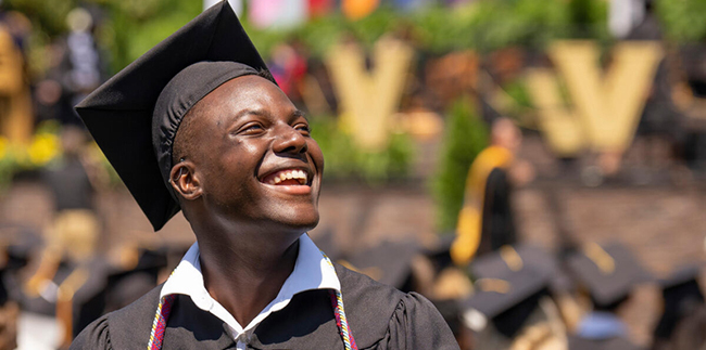 Young man looking up and smiling at 2022 Commencement