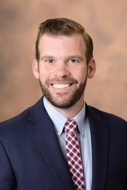 man in blue suit, gray collard shirt, and red tie