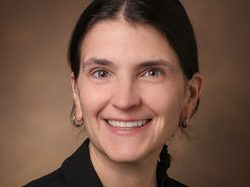 woman with brown hair in black suit jacket and blouse