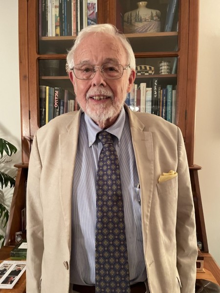 photograph of Vanderbilt Divinity alumnus Wilson Yates wearing tan jacket and standing in front of bookcase