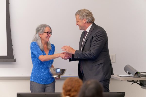 Meg Saylor accepts Chancellor's Cup and shakes hand of Chancellor Daniel Diermeier 