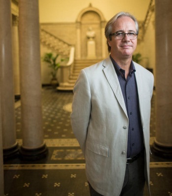 photograph of Kevin Murphy wearing white jacket in front of staircase at Cohen Hall