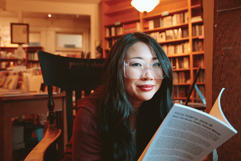 Jenny Qi wearing glasses reading a book