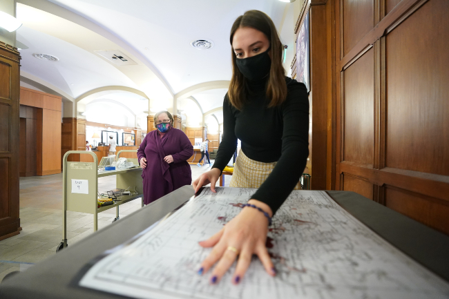 Buchanan Library Fellow Lia Okenkova installs her exhibit, “Depictions of Leprosy: Isolation for the Ages,” at Central Library.