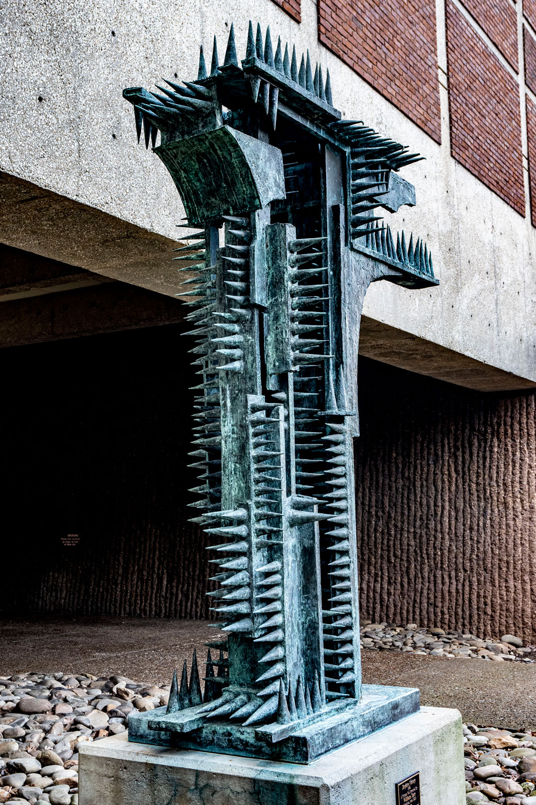 A large, bluish, cast bronze sculpture with lots of spikes sticking from it