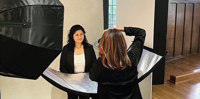 A female graduate student smiles while her professional headshot is taken