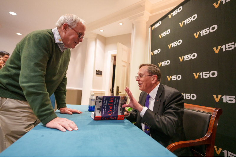 Gen. David Petraeus (right) signs copies on his recently published book, <i>Conflict: The Evolution of Warfare from 1945 to Ukraine,</i> at the John Seigenthaler Center on Nov. 10. (Harrison McClary/Vanderbilt)