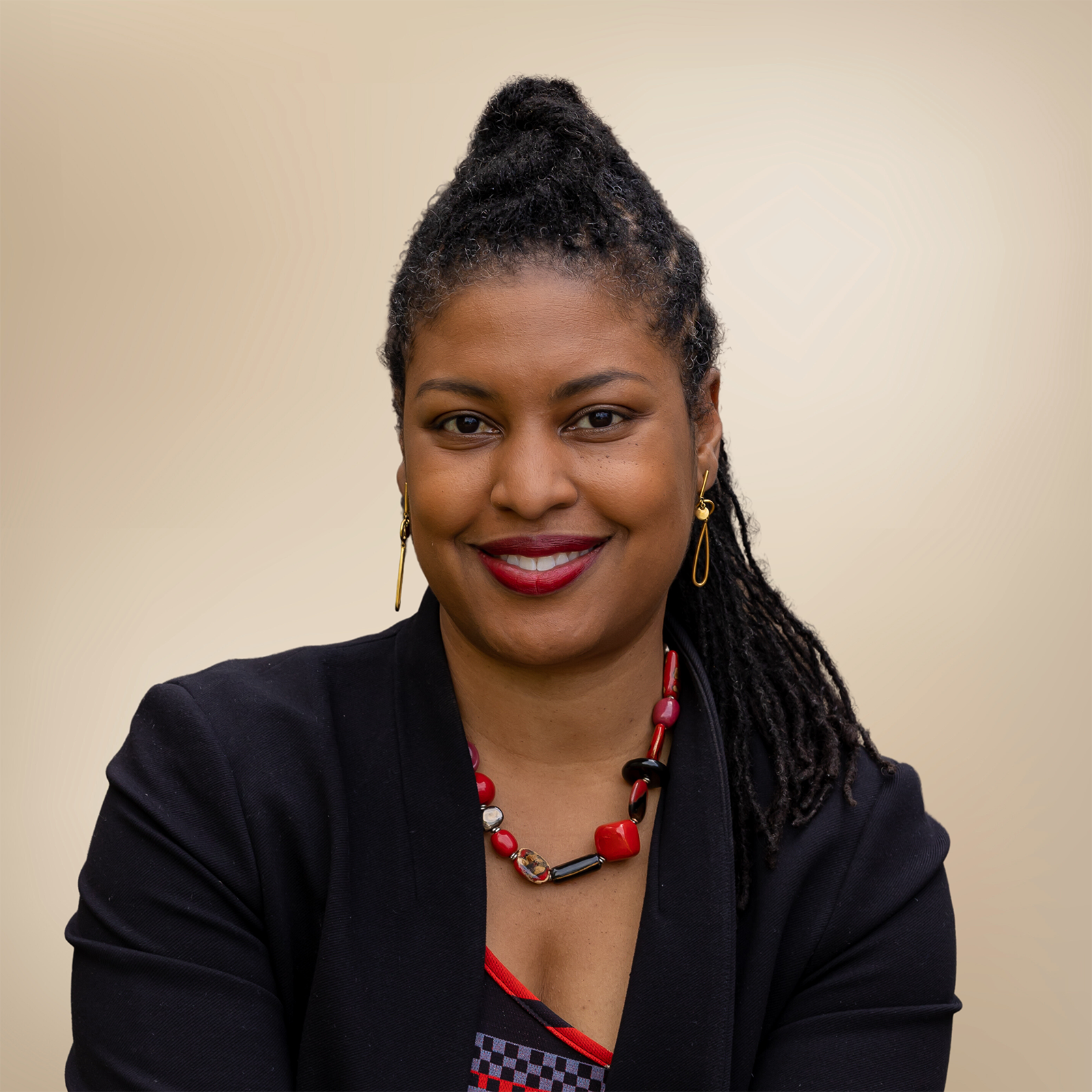 Portrait shot of Aisha Francis, president and CEO of Franklin Cummings Tech in Boston, wearing a black suit and posed against a light gold background