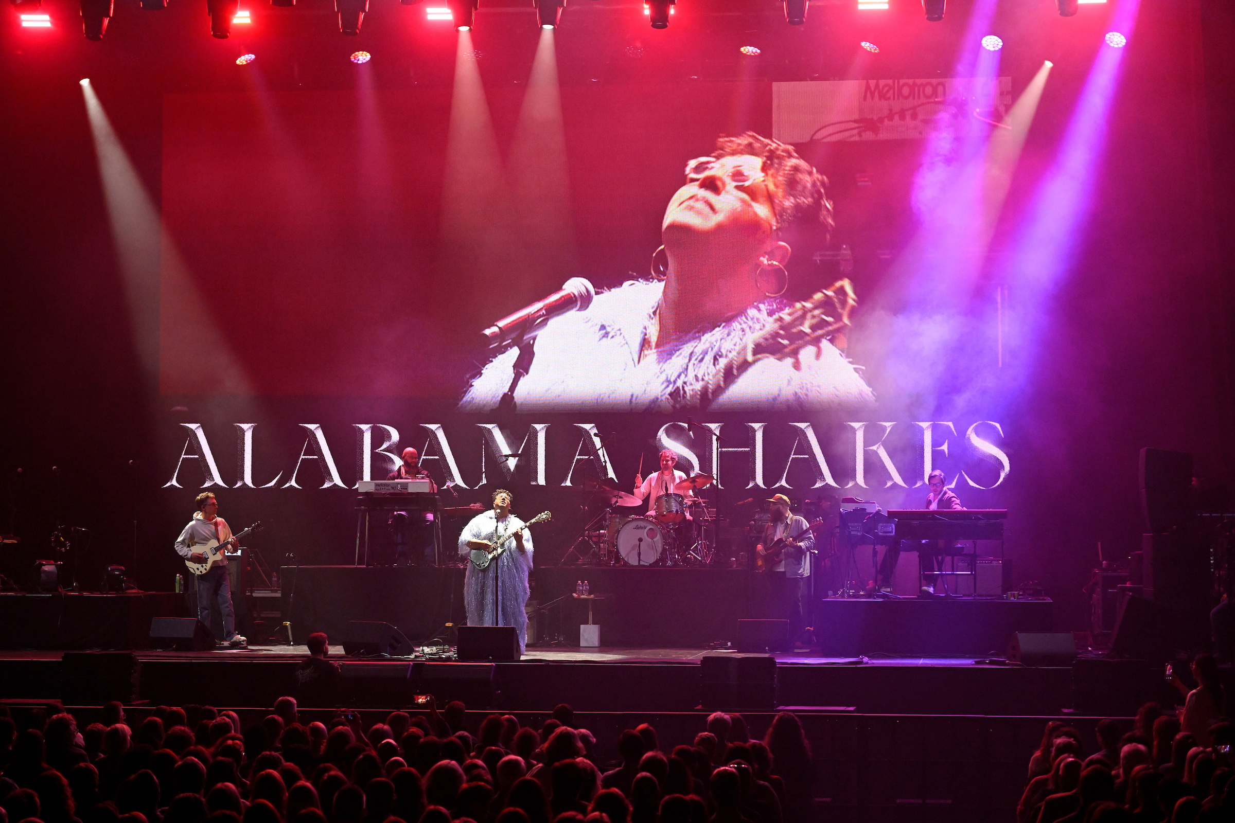 Alabama Shakes performing on stage with a video feed in the background