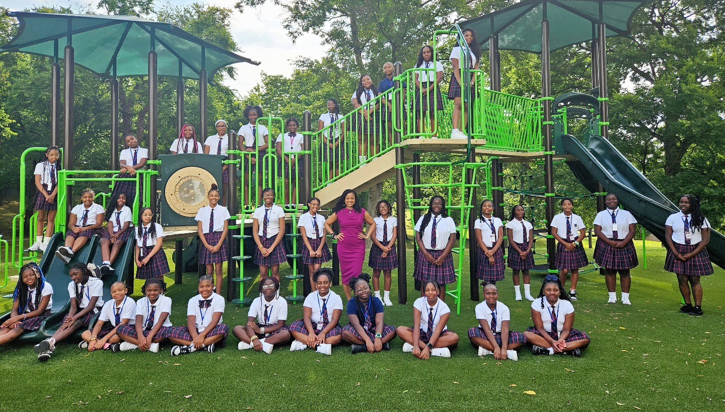 Group of students sit in front of playground
