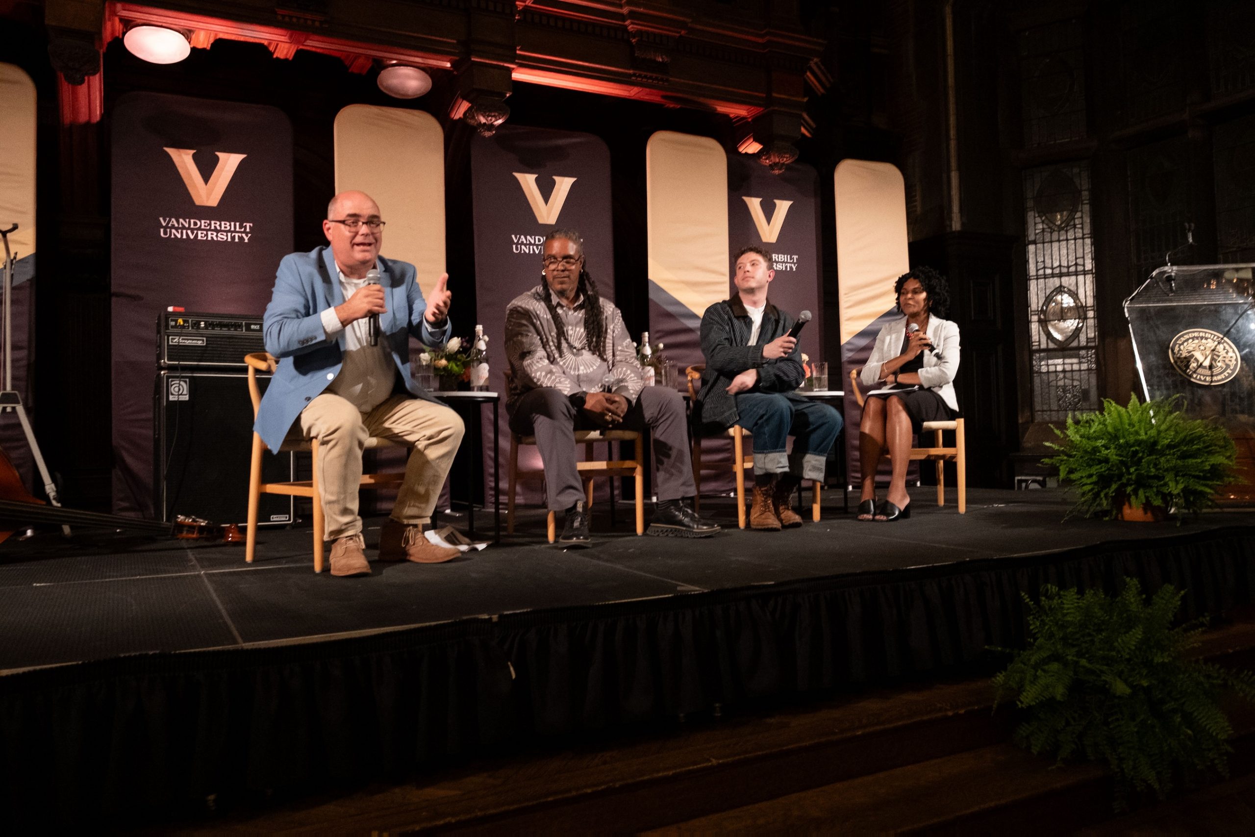 A panel of people sit on stage with Vanderbilt banners in the background