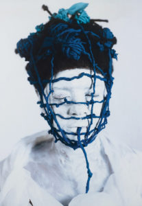 a photo of Campos-Pons in white makeup with blue string wrapped around her head