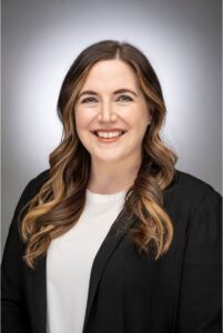 woman with long hair in a black blazer and white blouse