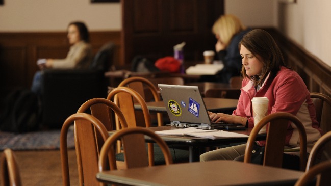 student sitting at a table working on a laptop