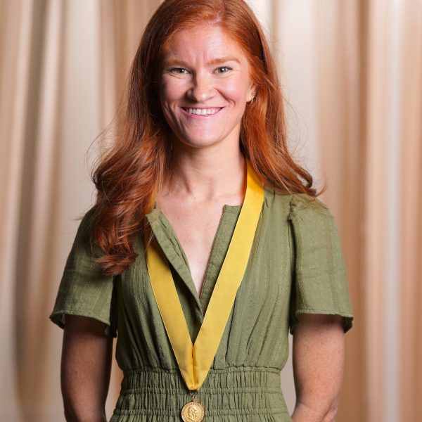 Sarah Moore in a green dress, wearing the gold Founder's Medal on a gold ribbon