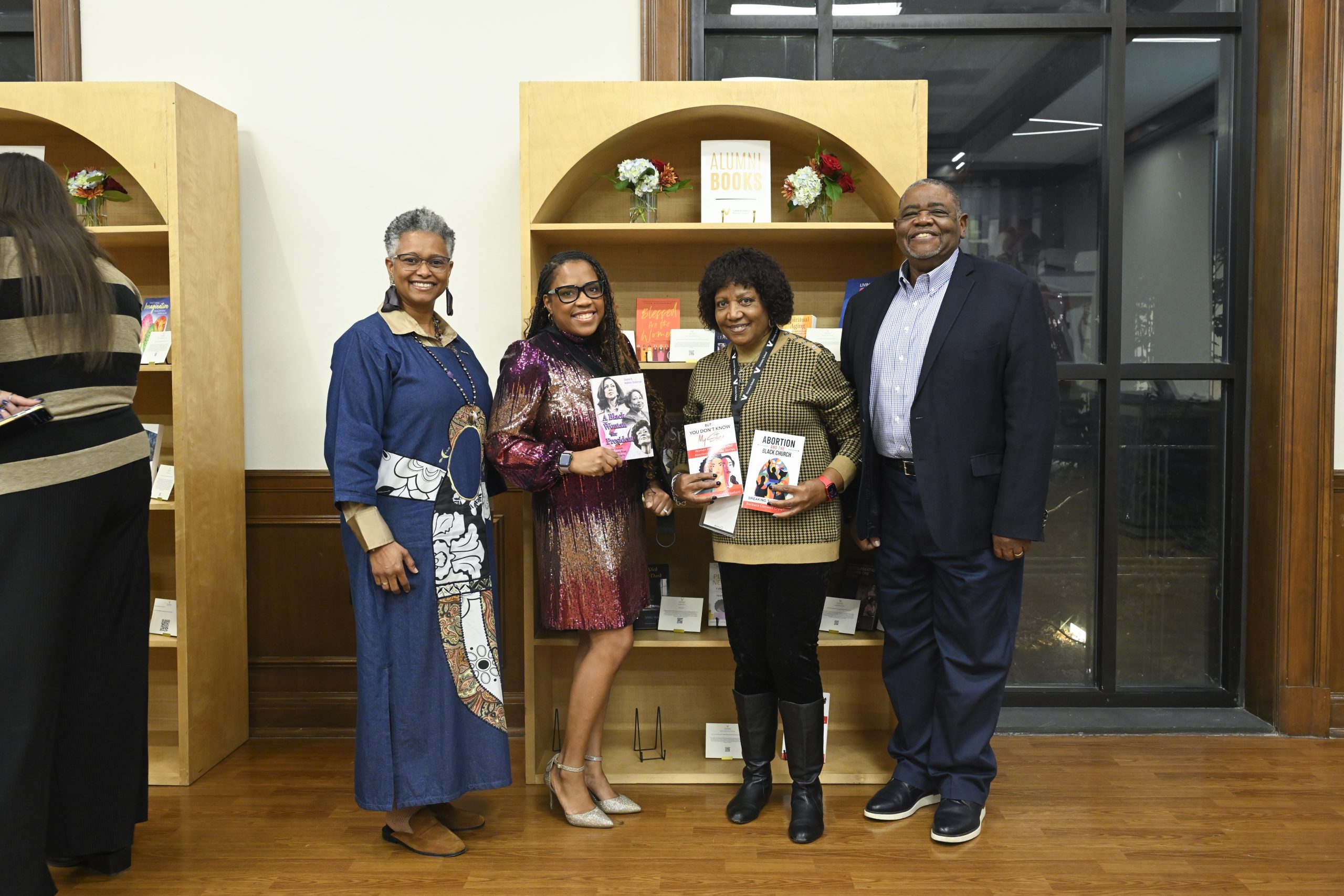 People gather for a photo and hold their books in front of the bookshelf display