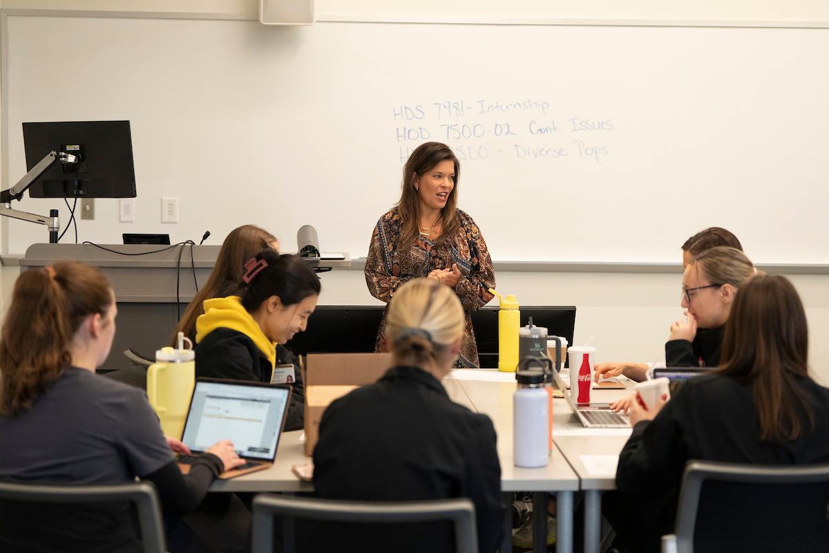 Teacher standing at the front of a college classroom giving a lecture