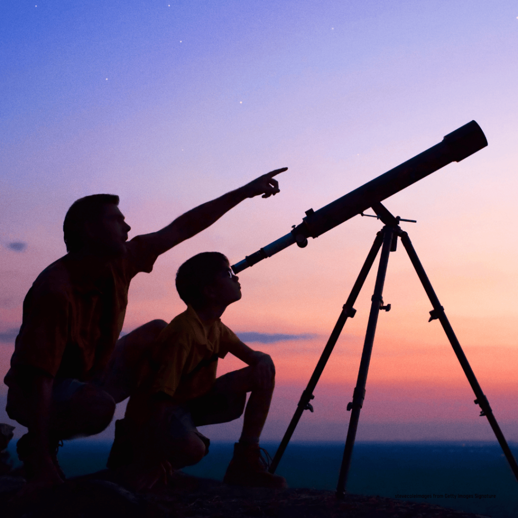 Man and child viewing with a telescope at dusk