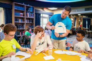 Dr. Billy Teets demonstrates the construction of a paper star wheel to seated students