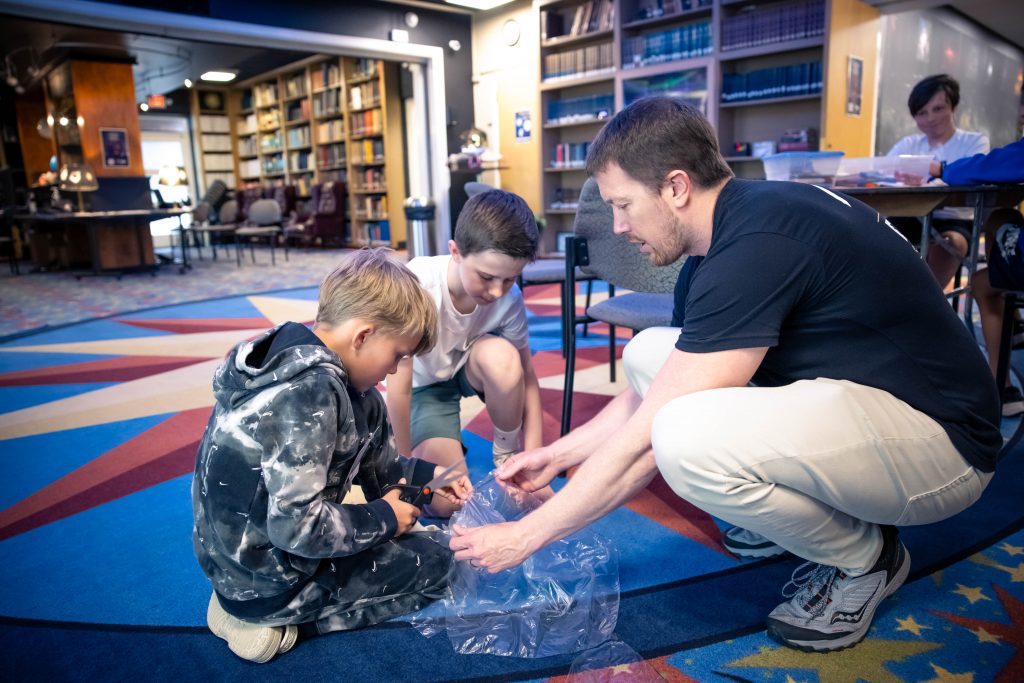 tudents work to construct a parachute from a plastic sheet.