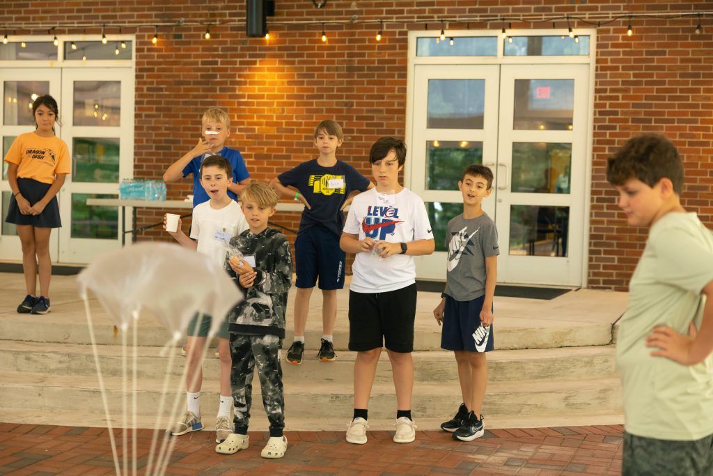 Students look on in excitement as a lander parachutes down to the hard surface below.