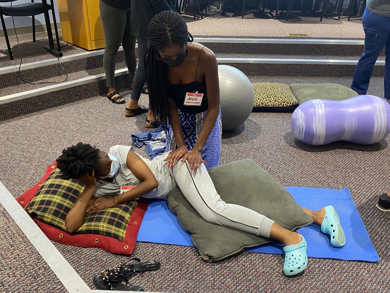 two people, one lying down and the other pushing on her hip with two hands