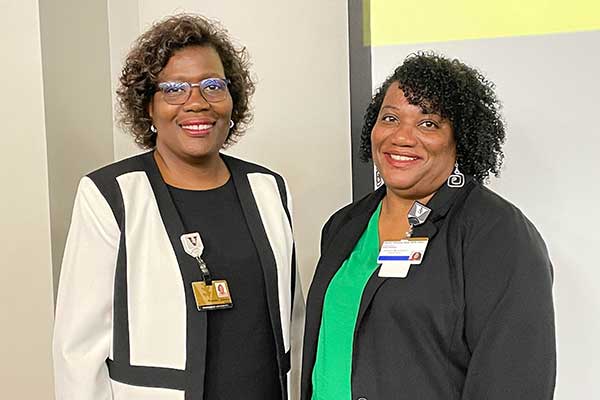 Two women of color stand next to each other in a classroom