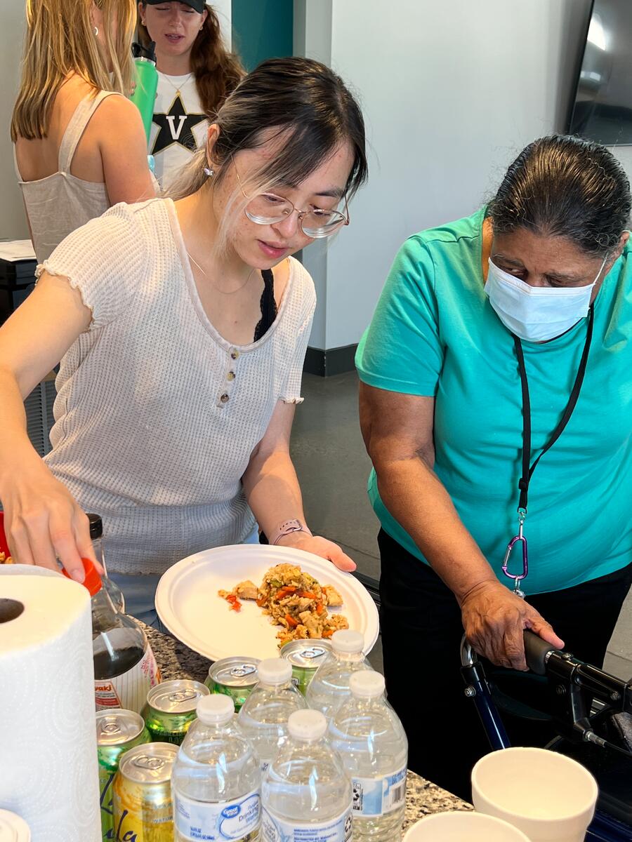 two people standing fix a plate of food