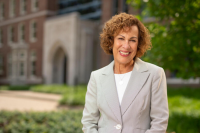 person smiling, standing outside in front of the nursing school building