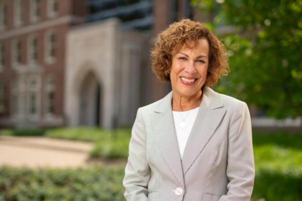 person smiling, standing outside in front of the nursing school building