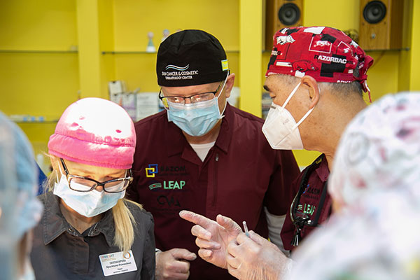 A group of people in medical scrubs and masks gather around an unseen patient