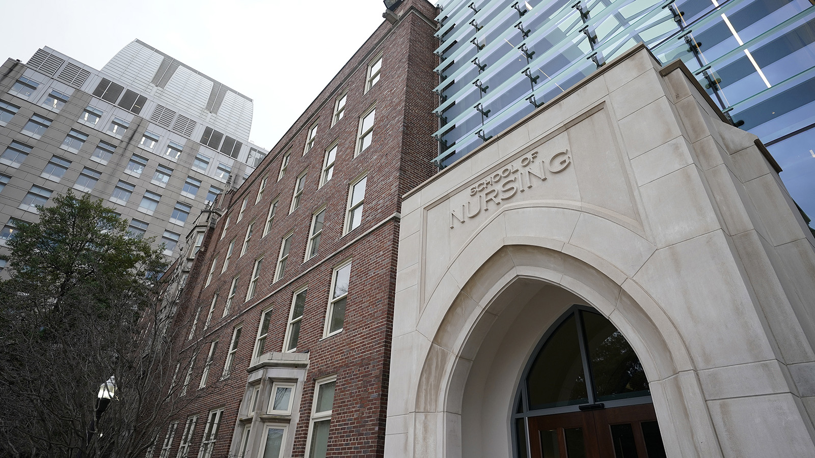 A brick and limestone building with School of Nursing engraved above the door