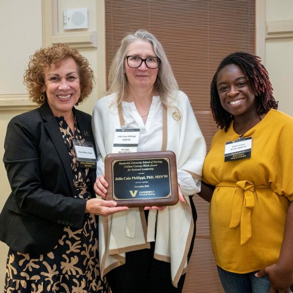 Three women holding an award and smiling for the camera.