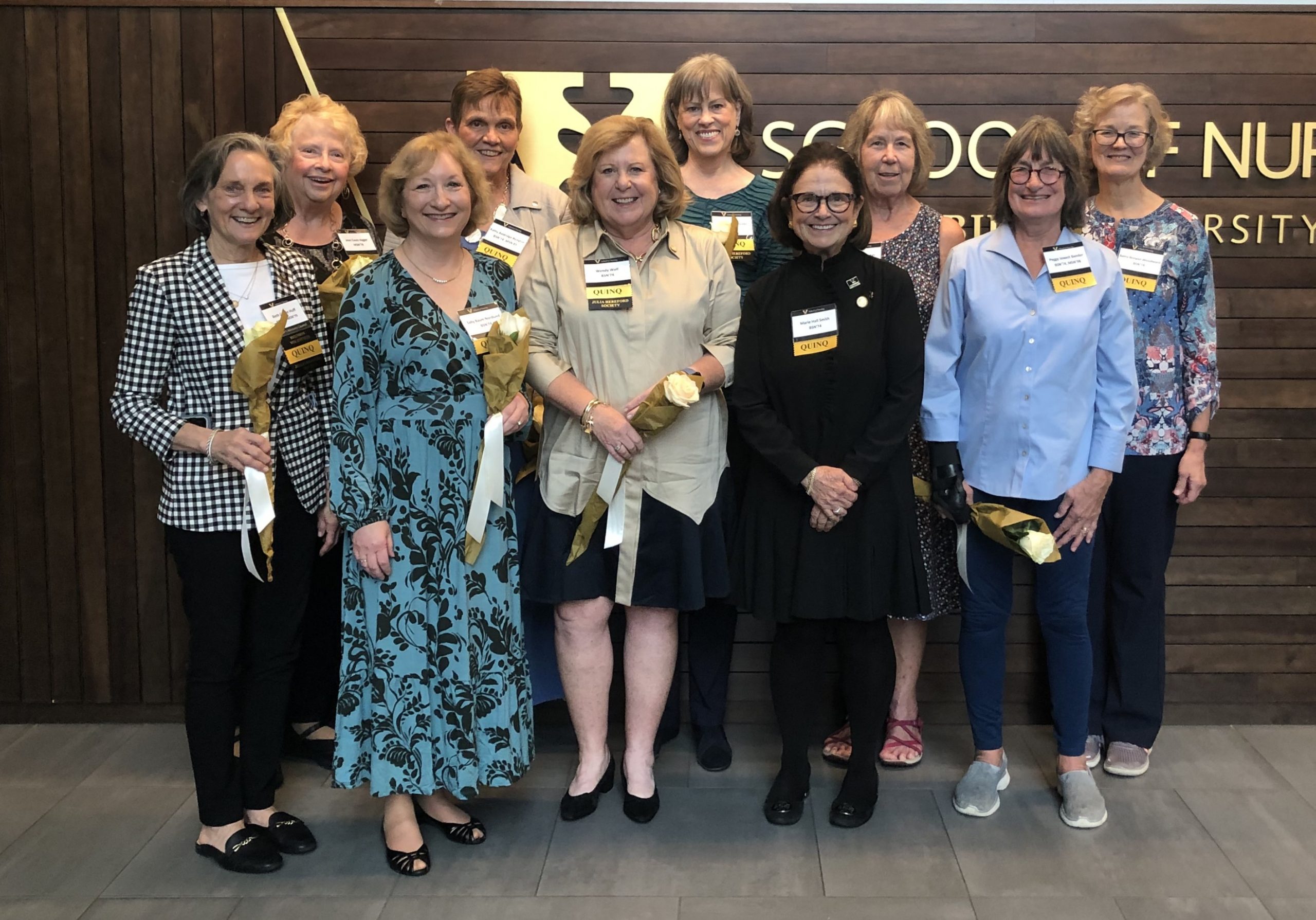 Ten women pose in front of wood backdrop that says Vanderbilt School of Nursing. All are smillng.