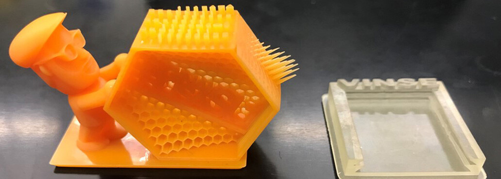 Resolution test print in orange resin (left) and holder for paper microfluidic cartridge in clear resin (right)