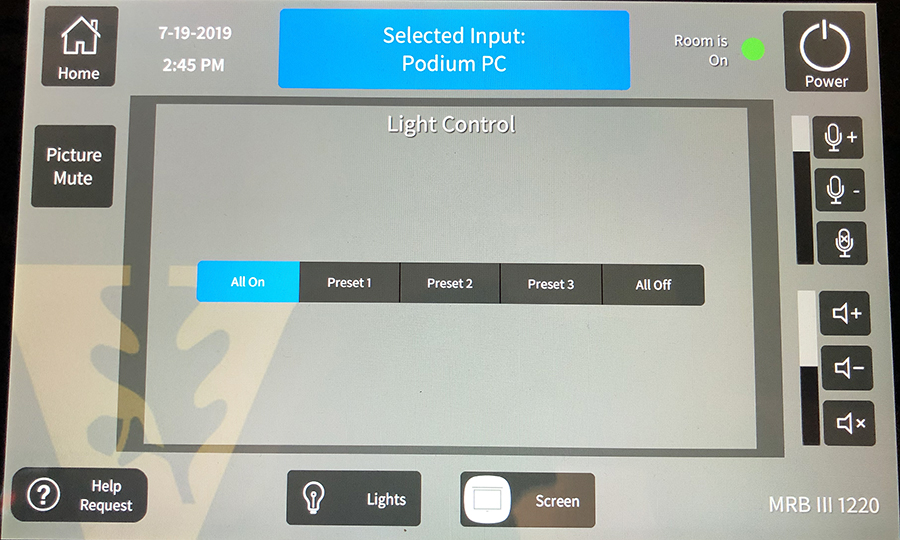 Photo of the control panel. At the top it says "Selected Input: Podium PC." The middle of the control panel says "Light Control" and shows 5 options listed side by side: All On, Preset 1, Preset 2, Preset 3, and All Off.