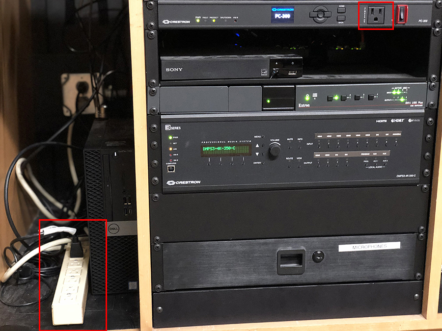 Photo zoomed in on the bottom section of the podium. On the left, by the Dell, is a white power strip. An additional outlet is at the top right of the image.