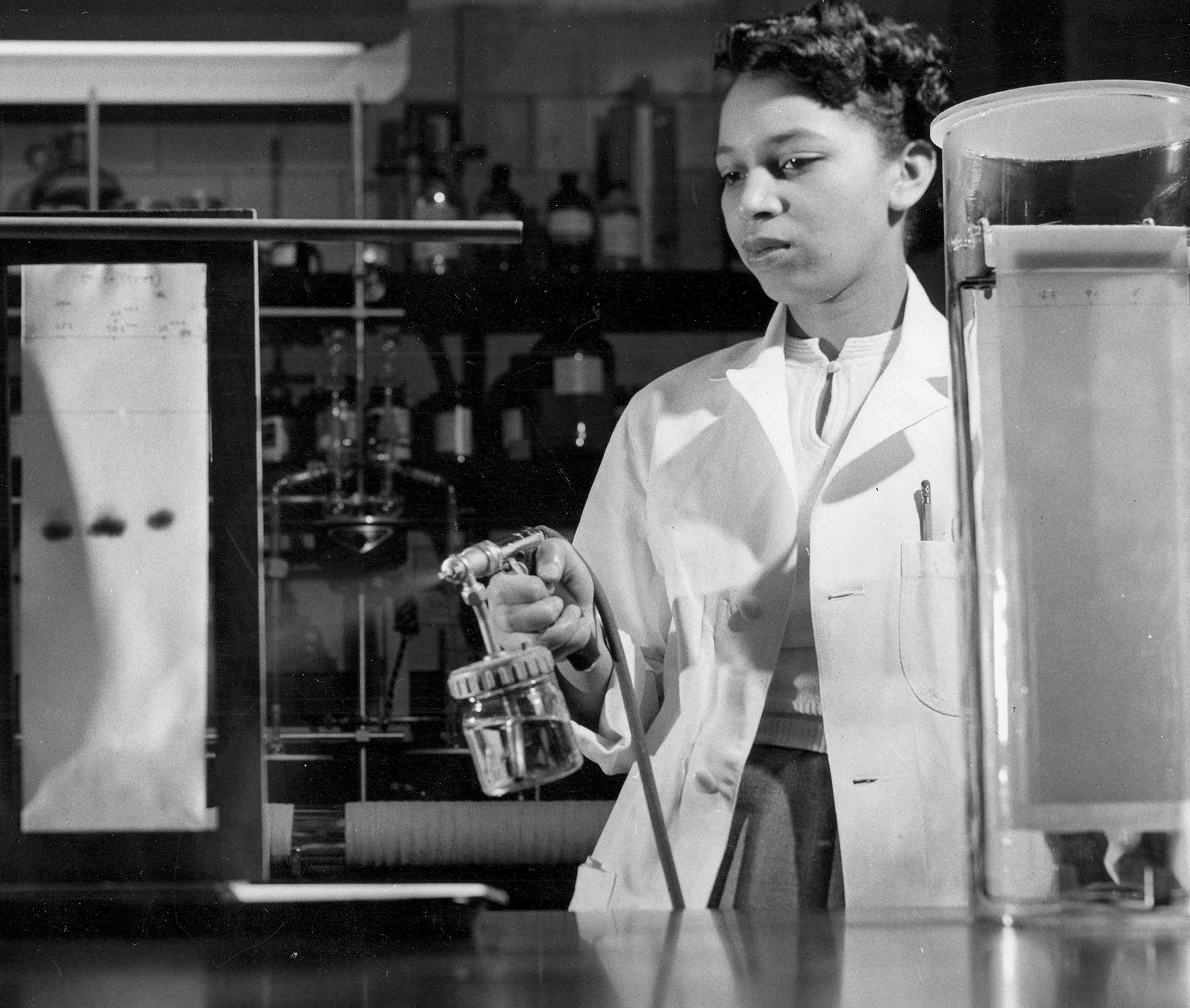 Black and white photo of Alma Levant Hayden conducting an experiment in her lab.
