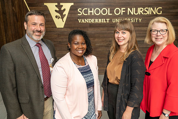 Vanderbilt nursing faculty standing in front of VUSN sign on wood wall